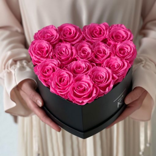 Herzförmige Rosenbox mit lila pinken Infinityrosen wird in den Händen gehalten