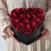 Herzförmige Rosenbox mit roten Infinityrosen wird in den Händen gehalten
