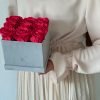 Eckige Rosenbox mit Samtfinish und roten Infinityrosen wird von einer Frau in den Händen gehalten